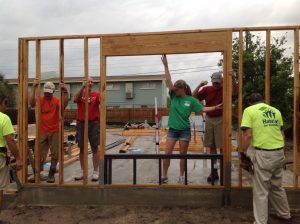 Future homeowner, Jennifer, helps volunteers raise walls on her home.